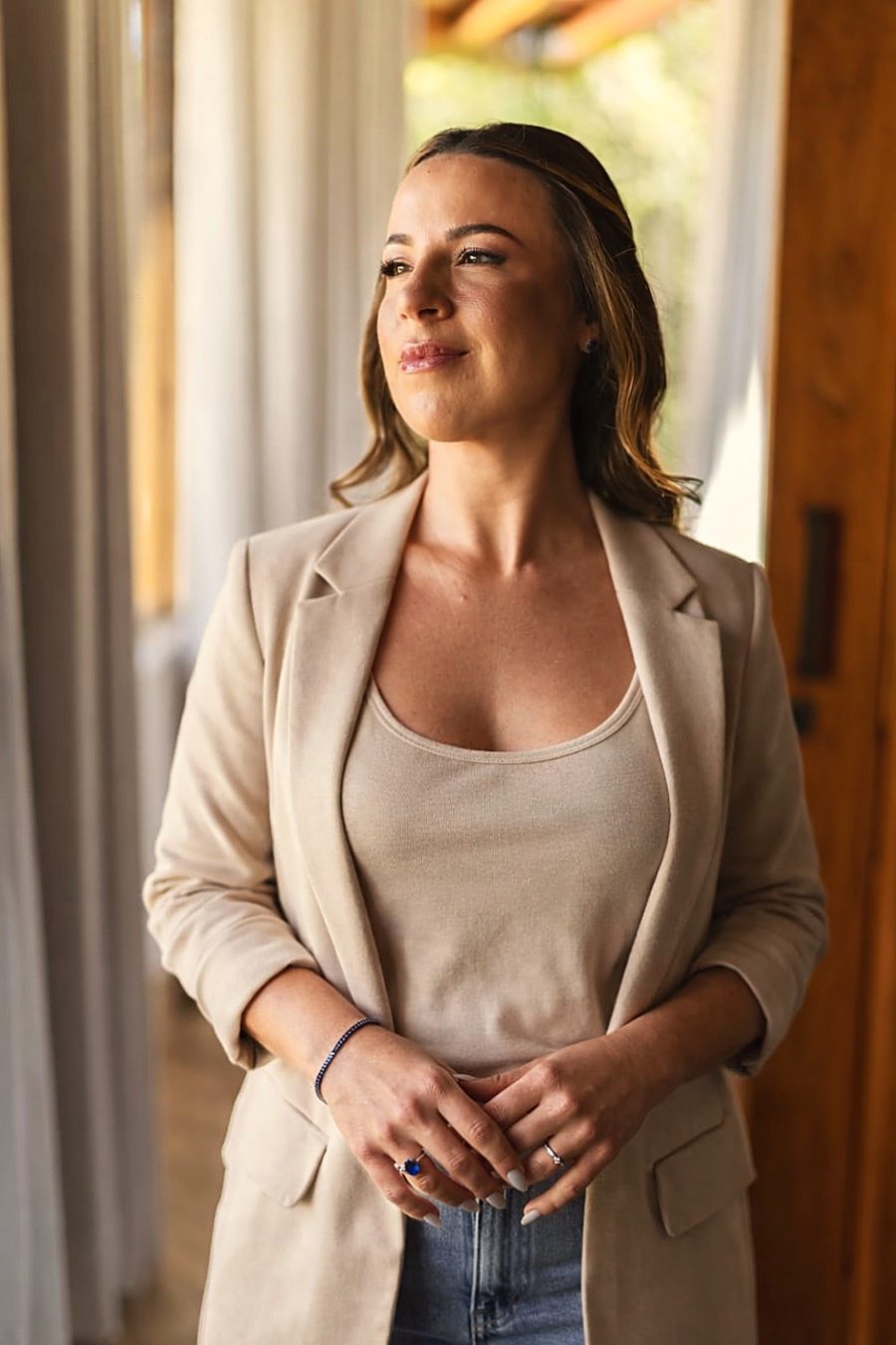 Mariana Bovo, terapeuta integrativa, sorrindo junto à janela
